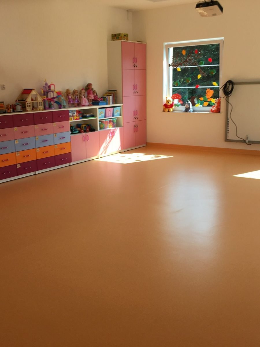 Układanie jasnej wykładziny elastycznej w kolorowej sali przedszkolnej na terenie Suwałk